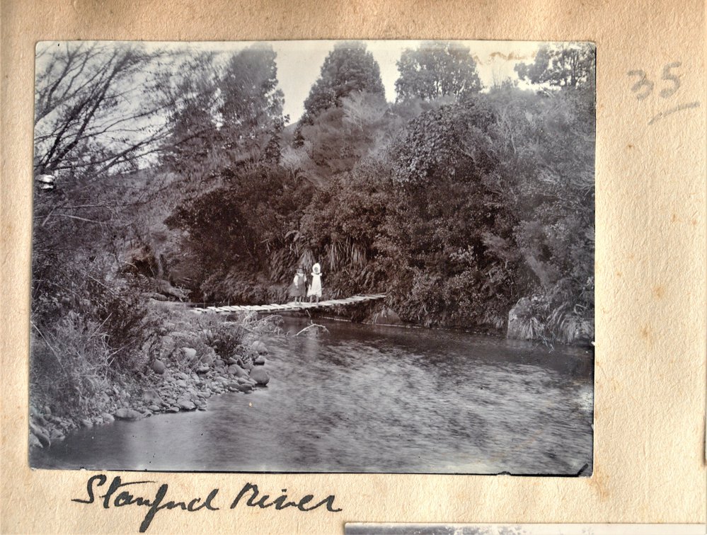 Two girls standing on a bridge over a river near Stanford at Katikati.